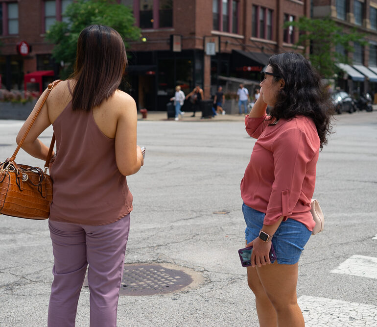 Two women looking down the street as if they are trying to get a sense of their bearings.